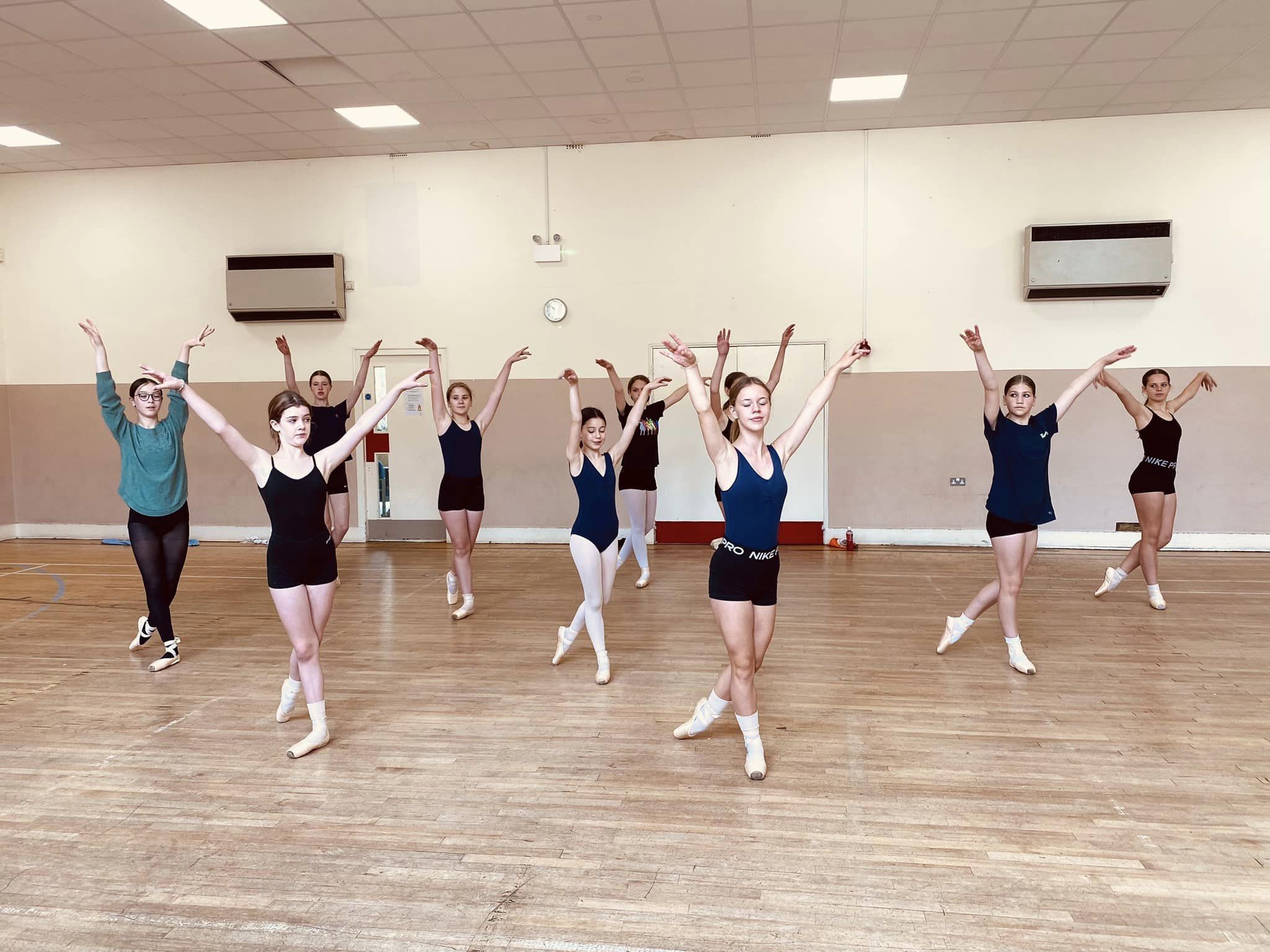 a group of students in a hall practicing ballet